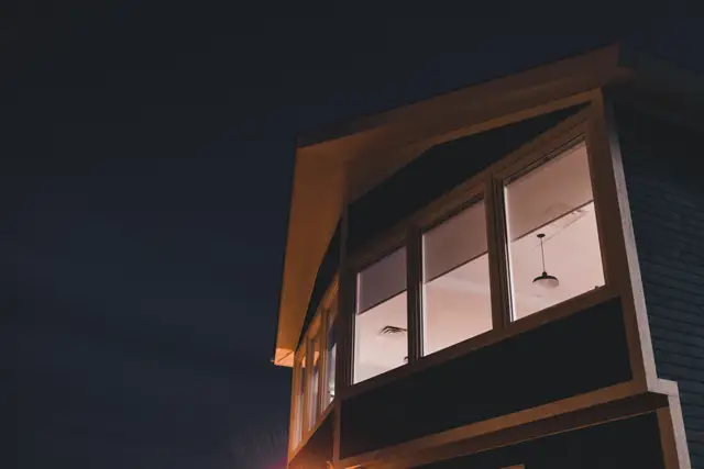 A modern house with tall windows glowing at night