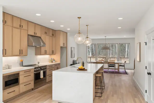 A kitchen with a marble island and pendant lights
