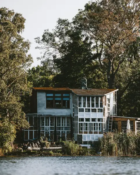 A white modern house on the water framed by old trees