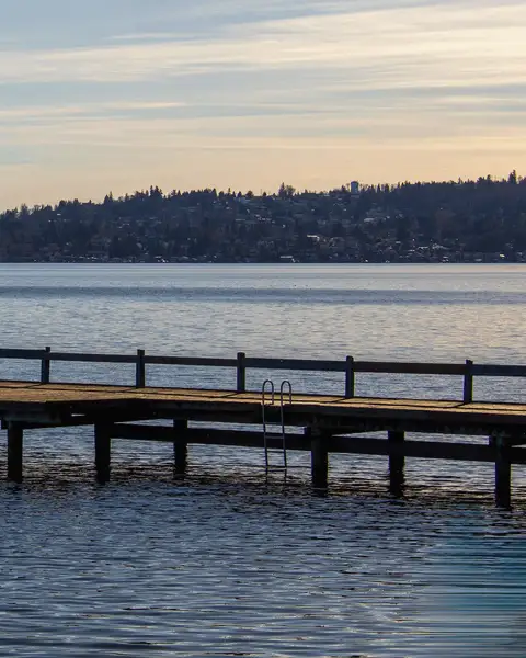 A wooden dock reaching into a lake at sunset