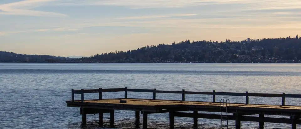 A wooden dock reaching into a lake at sunset