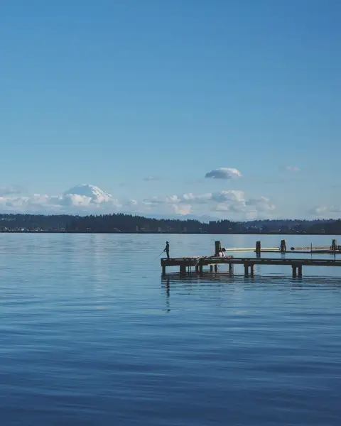 A dock reaching into a calm lake under a blue sky