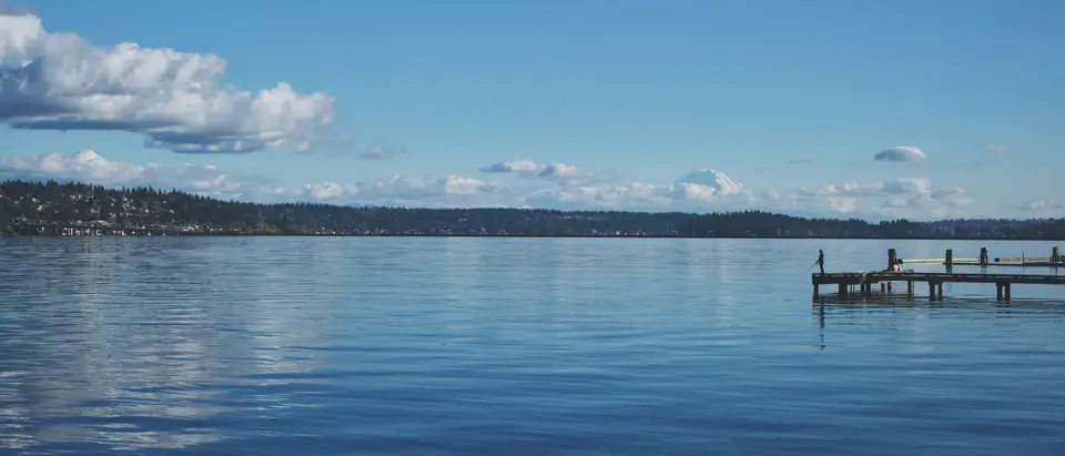 A dock reaching into a calm lake under a blue sky