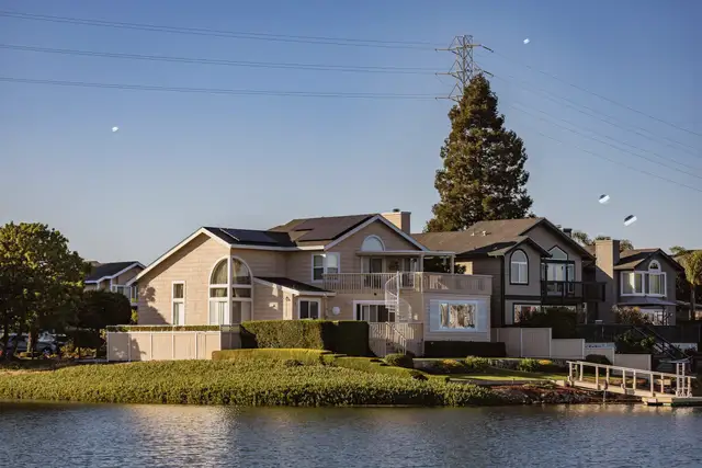 A row of houses along a calm lake shore under a blue sky